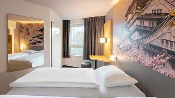 Habitación de hotel con una cama grande, una mesita de noche, un espejo y una pared decorada con un mural de arquitectura tradicional.