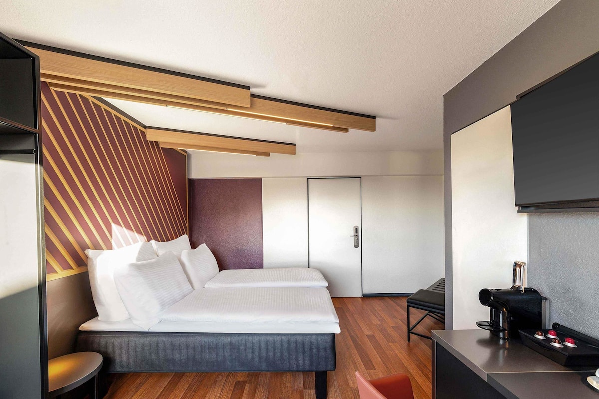 Une chambre d’hôtel moderne équipée d’un lit, d’un bureau et d’une machine à café.