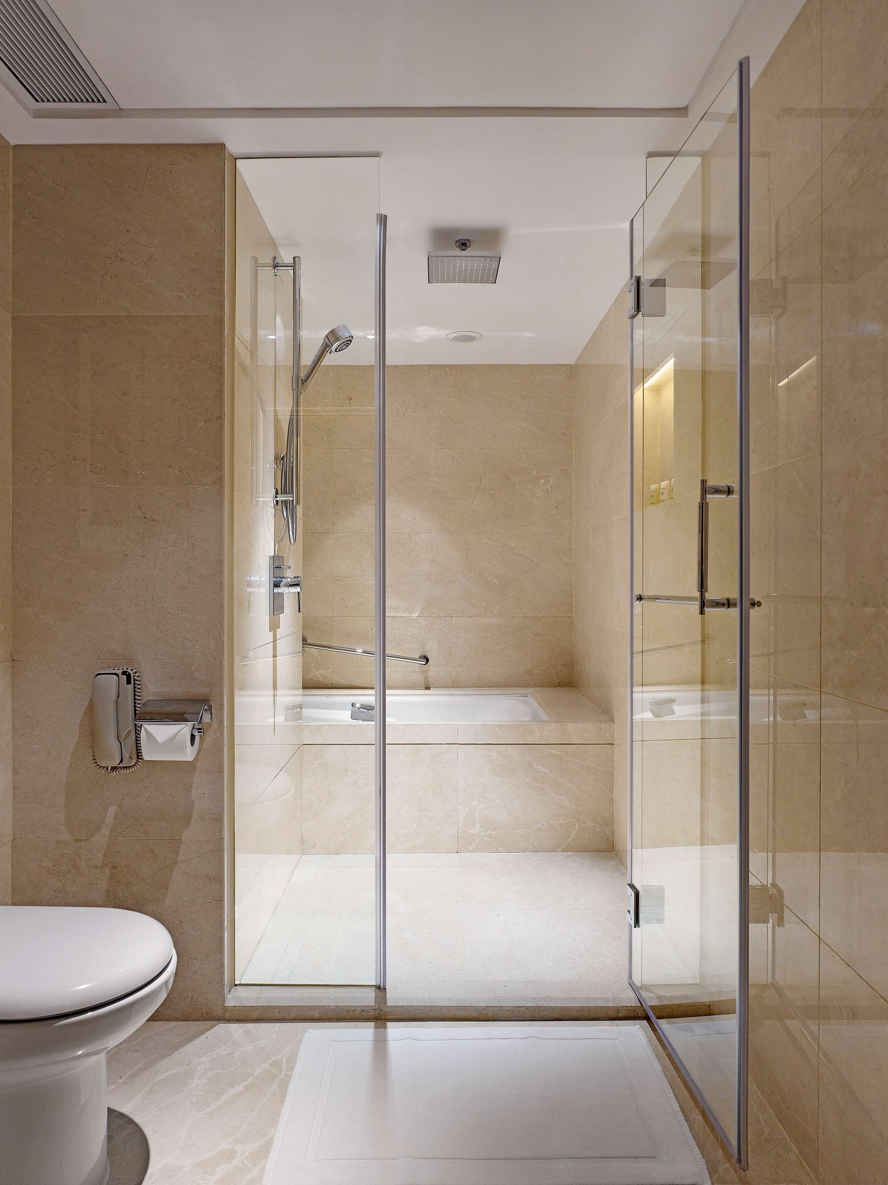 Une salle de bain moderne avec une douche à parois de verre, une baignoire visible et des toilettes.