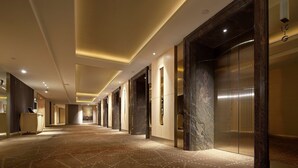 A long, well-lit hallway with marble walls and a patterned carpet.
