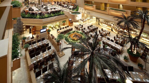 A multi-level atrium with a central courtyard, multiple dining areas, and balconies with plants.