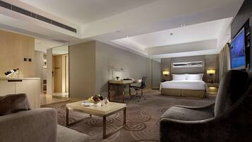 Ein modernes Hotelzimmer mit Bett, Schreibtisch, Stuhl, Couchtisch und Fernseher.