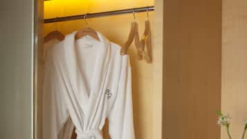 A wooden vanity with a mirror, a robe hanging on a rack, and a small plant on the counter.