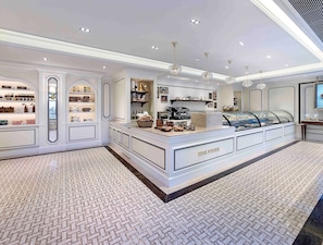 A luxurious fine foods display area with a marble counter, elegant lighting, and a patterned floor.