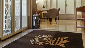 Un hall d’hôtel comprenant un comptoir d’accueil, des chaises, une poubelle et une porte dotée de panneaux en verre dépoli.