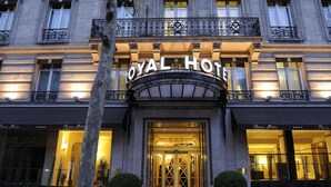 L’extérieur du Royal Hotel se distingue par son imposante entrée, ses grandes fenêtres et un balcon agrémenté de balustrades décoratives.