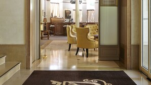 Un hall d’hôtel avec une entrée imposante, un lustre et un comptoir d’accueil.