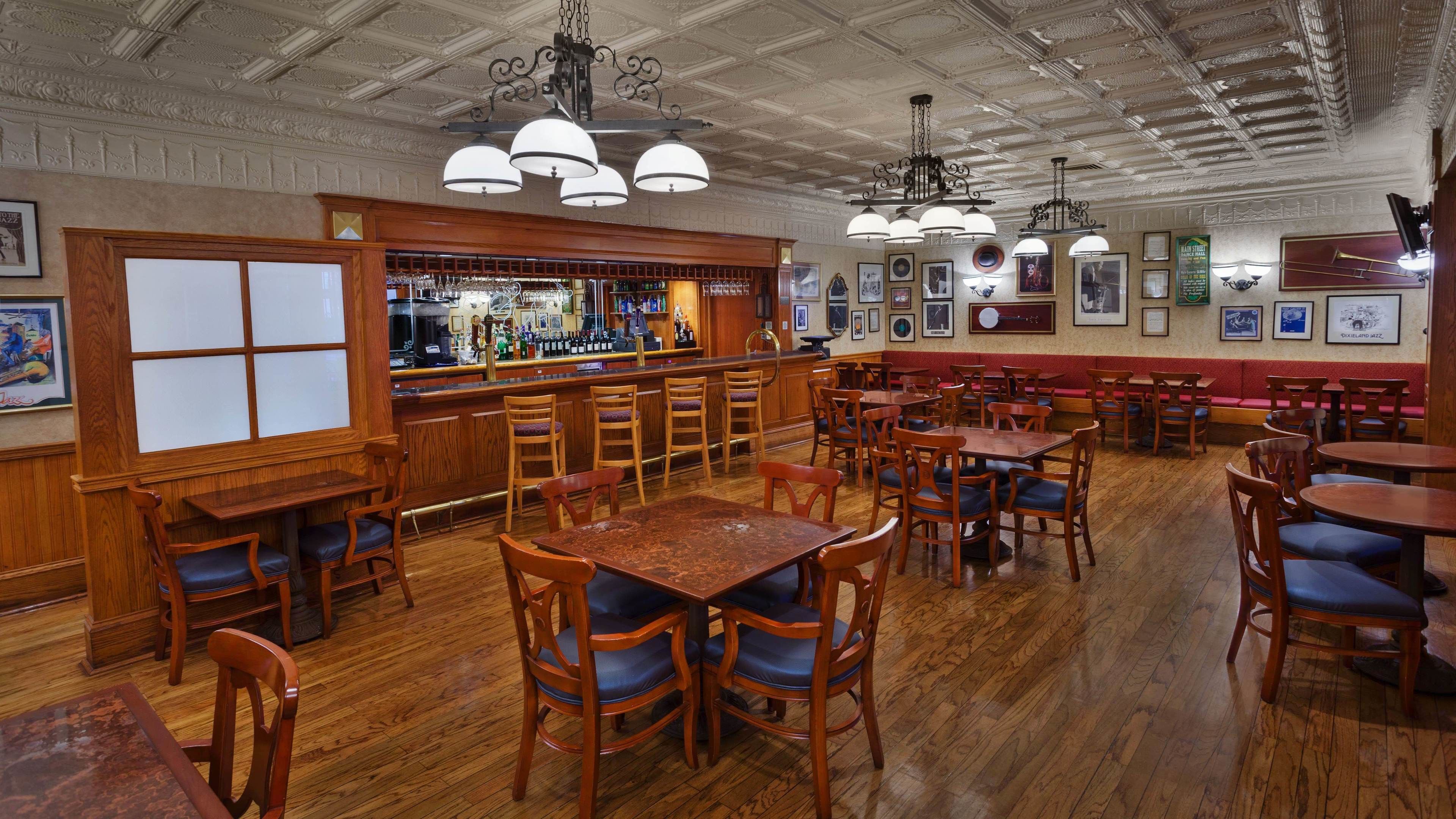 A restaurant with wooden furniture, a bar area, and framed pictures on the walls.