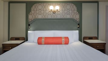 Una habitación de hotel con una cama grande, dos mesitas de noche, un cabecero decorativo y una lámpara fijada a la pared.