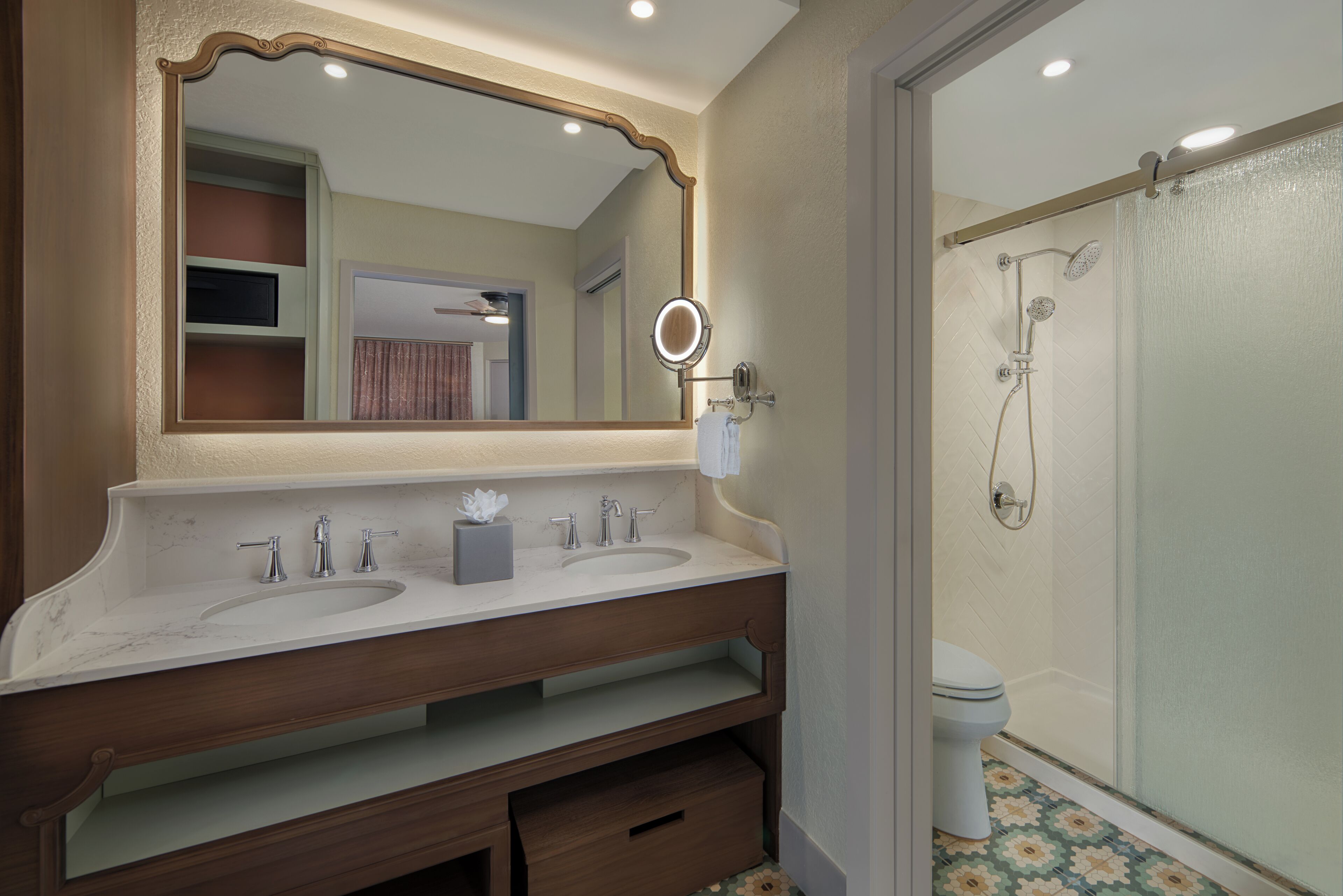 A bathroom with a double sink vanity, a large mirror, and a shower area.