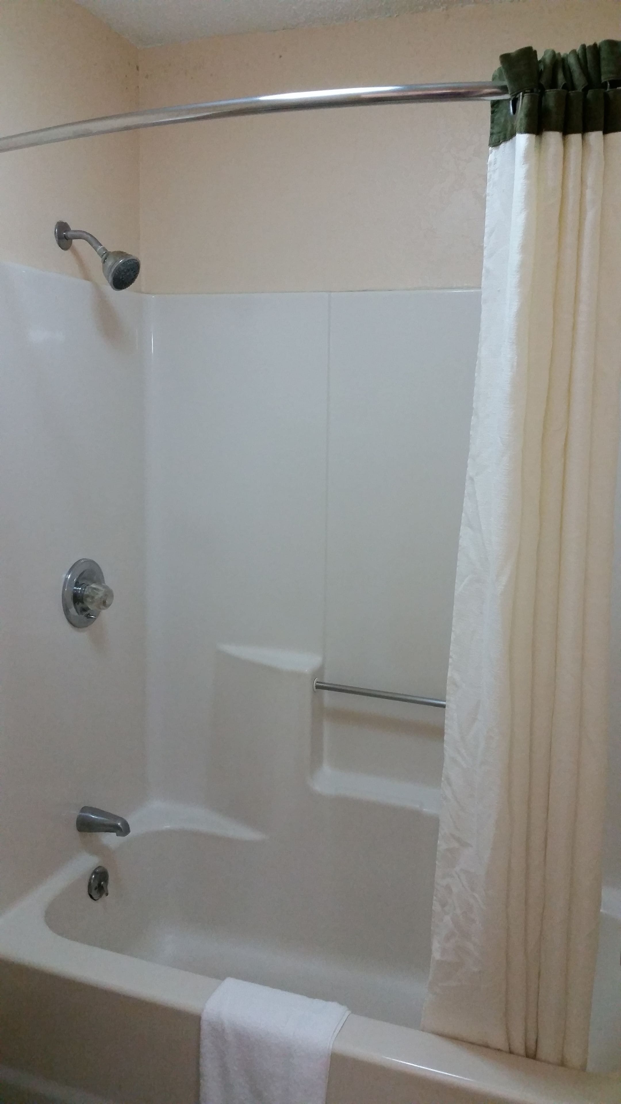 Une salle de bain équipée d’une baignoire, d’une pomme de douche, d’un porte-serviettes et d’un rideau.
