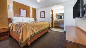 A hotel room with a bed, a desk, a TV, a ceiling fan, and a bathroom visible through an archway. - Super 8 by Wyndham Waco/Mall area TX (Waco)