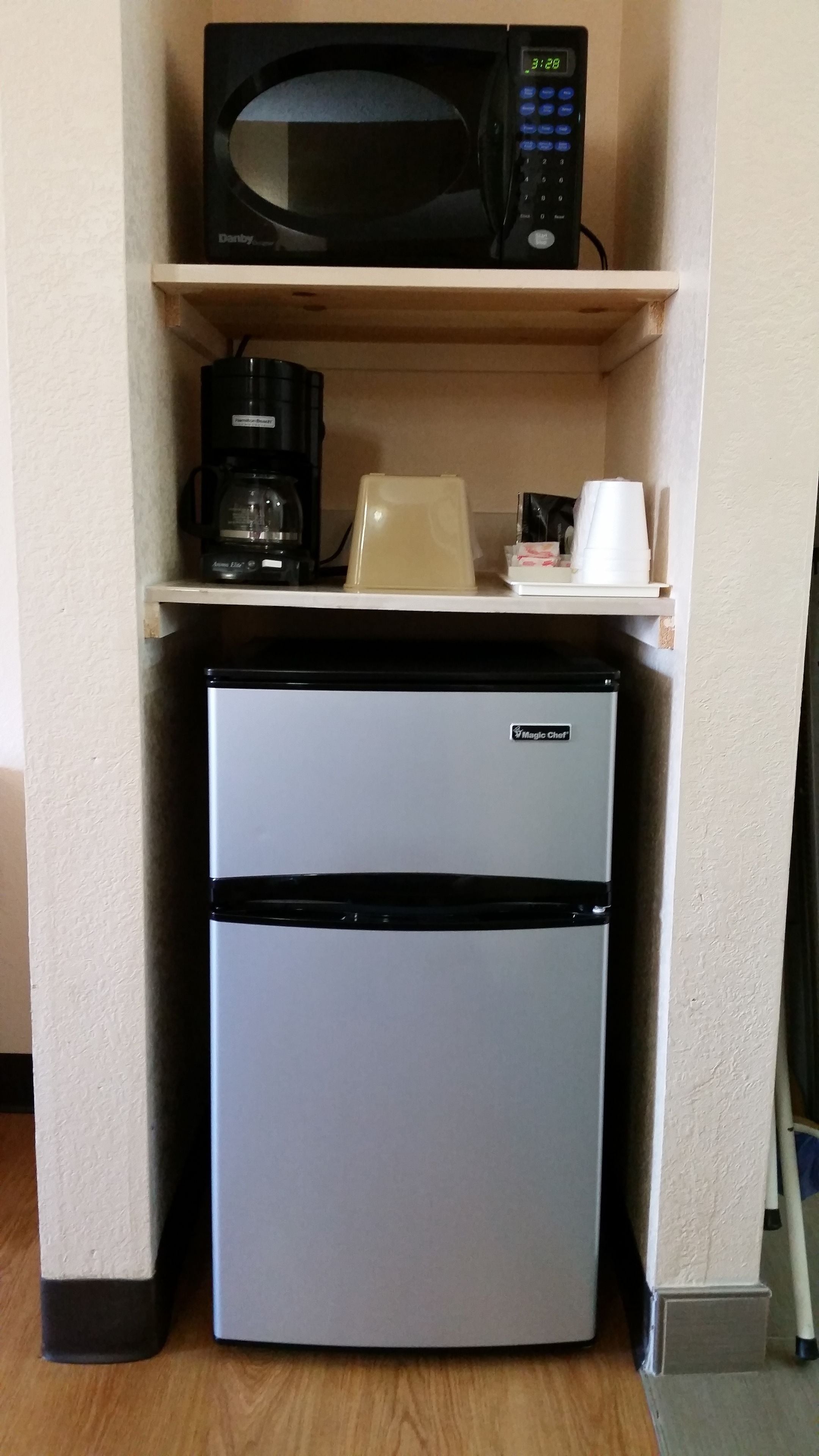 Uma cozinha compacta equipada com micro-ondas, cafeteira, torradeira e frigorífico.