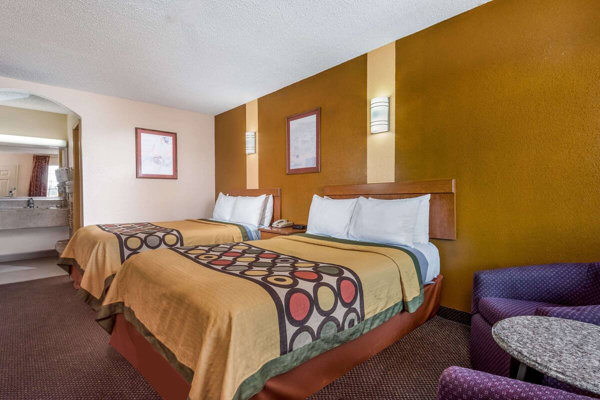 Una habitación de hotel con dos camas, una mesita y un sofá.