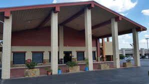 A building with a covered entrance, brick walls, and potted plants. - Super 8 by Wyndham Waco/Mall area TX (Waco)