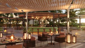 Un espace extérieur aménagé pour les repas, avec des tables, des chaises et un éclairage d’ambiance.