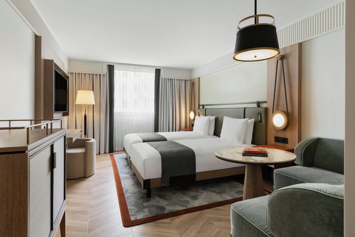Una habitación de hotel moderna con una cama grande, un escritorio, un televisor y un sofá.