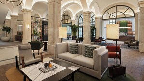 Un hall d’entrée spacieux avec un haut plafond en arc de cercle, un espace de détente central comprenant un canapé et des fauteuils, une table basse et une bibliothèque.