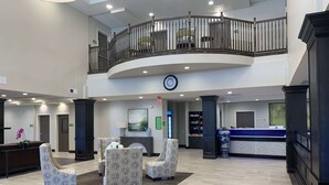 A spacious lobby with a reception desk, seating area, and a second-floor balcony.