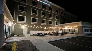 A Best Western Plus hotel with a covered outdoor seating area and a fire hydrant in front.