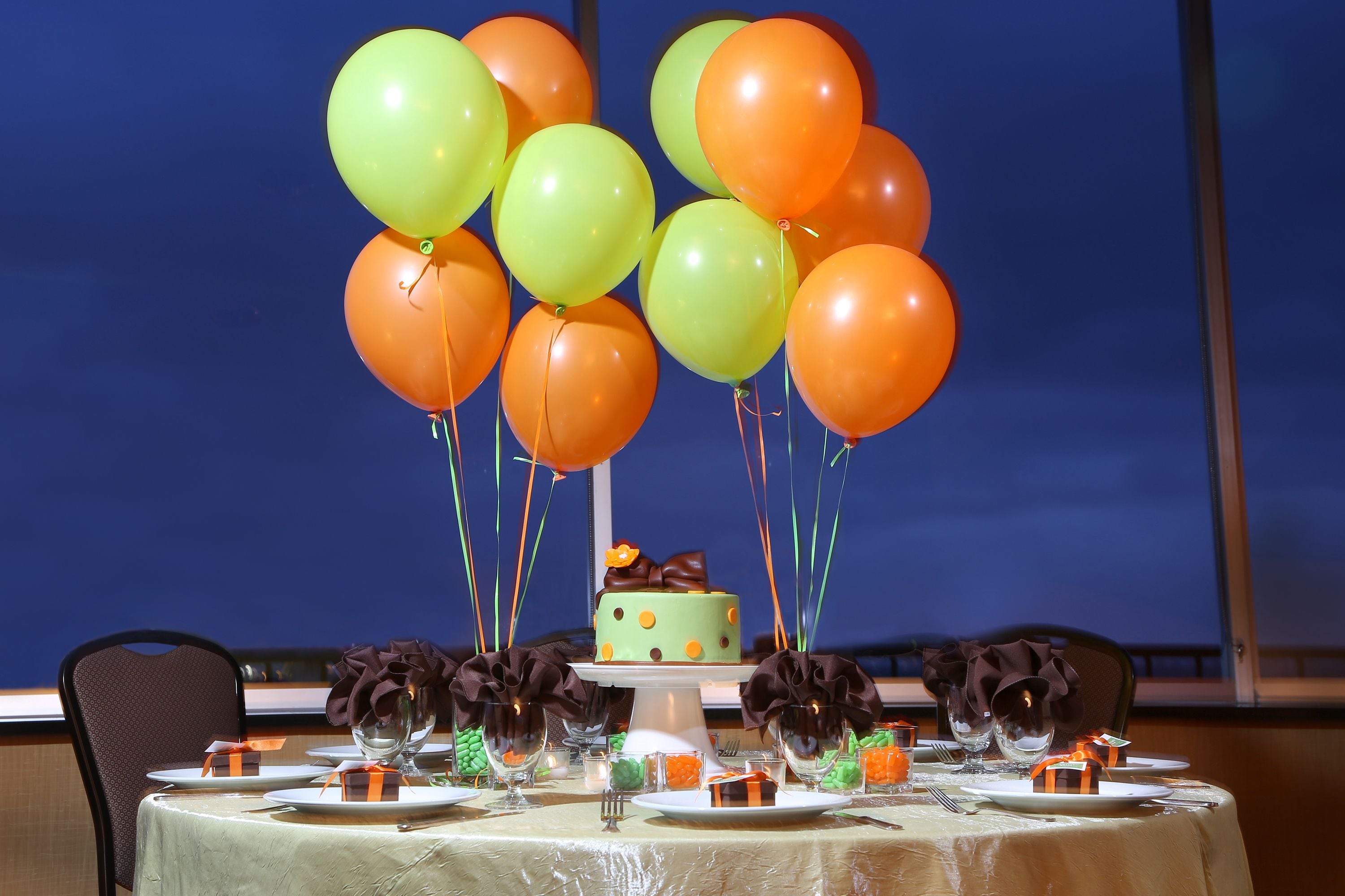 A table set for a meal with a cake centerpiece, surrounded by balloons.