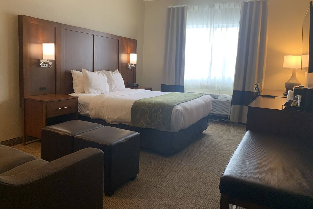 Ein Hotelzimmer mit einem Bett, einem Schreibtisch, einem Sessel, einer Couch und einem Fernseher.