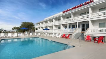 A hotel with a pool, red and white chairs, and a sign reading "SHENANIGG INN".