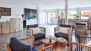A spacious lobby with a reception desk, seating area, and large windows offering a view of the outside. - Shem Creek Inn (Mount Pleasant)