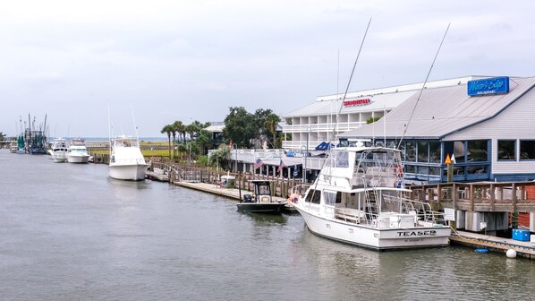 A marina with several boats docked, a waterfront restaurant named "Water's Edge," and a building with a sign indicating "TEASE" and "MT. PLEASANT, SC." - Shem Creek Inn (Mount Pleasant)