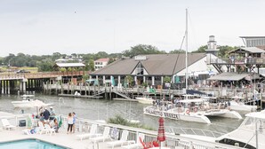 A marina with boats docked, a pool area with lounge chairs, and a sign for 'Palmetto Breeze'. - Shem Creek Inn (Mount Pleasant)