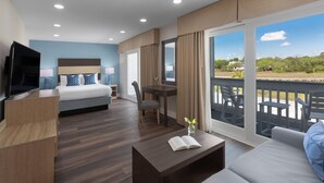 A modern hotel room with a bed, a desk, a TV, and a balcony with outdoor furniture. - Shem Creek Inn (Mount Pleasant)