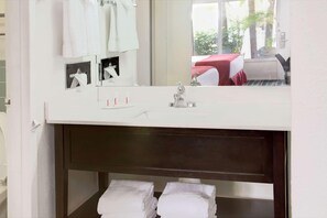 A bathroom with a white sink, a mirror, and two towels on the shelf. - Ramada by Wyndham Fort Lauderdale Airport/Cruise Port (Fort Lauderdale)
