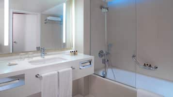 Un baño moderno con ducha envuelta en vidrio, tocador doble y un espejo grande.