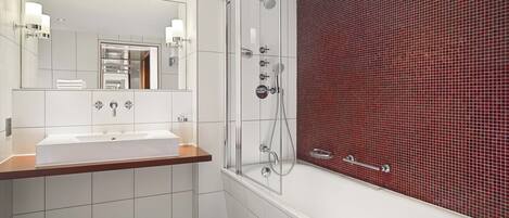 A modern bathroom with a glass-enclosed shower, a white sink, and a red-tiled wall.