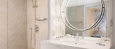Un baño moderno con un espejo grande, ducha y encimera de mármol.