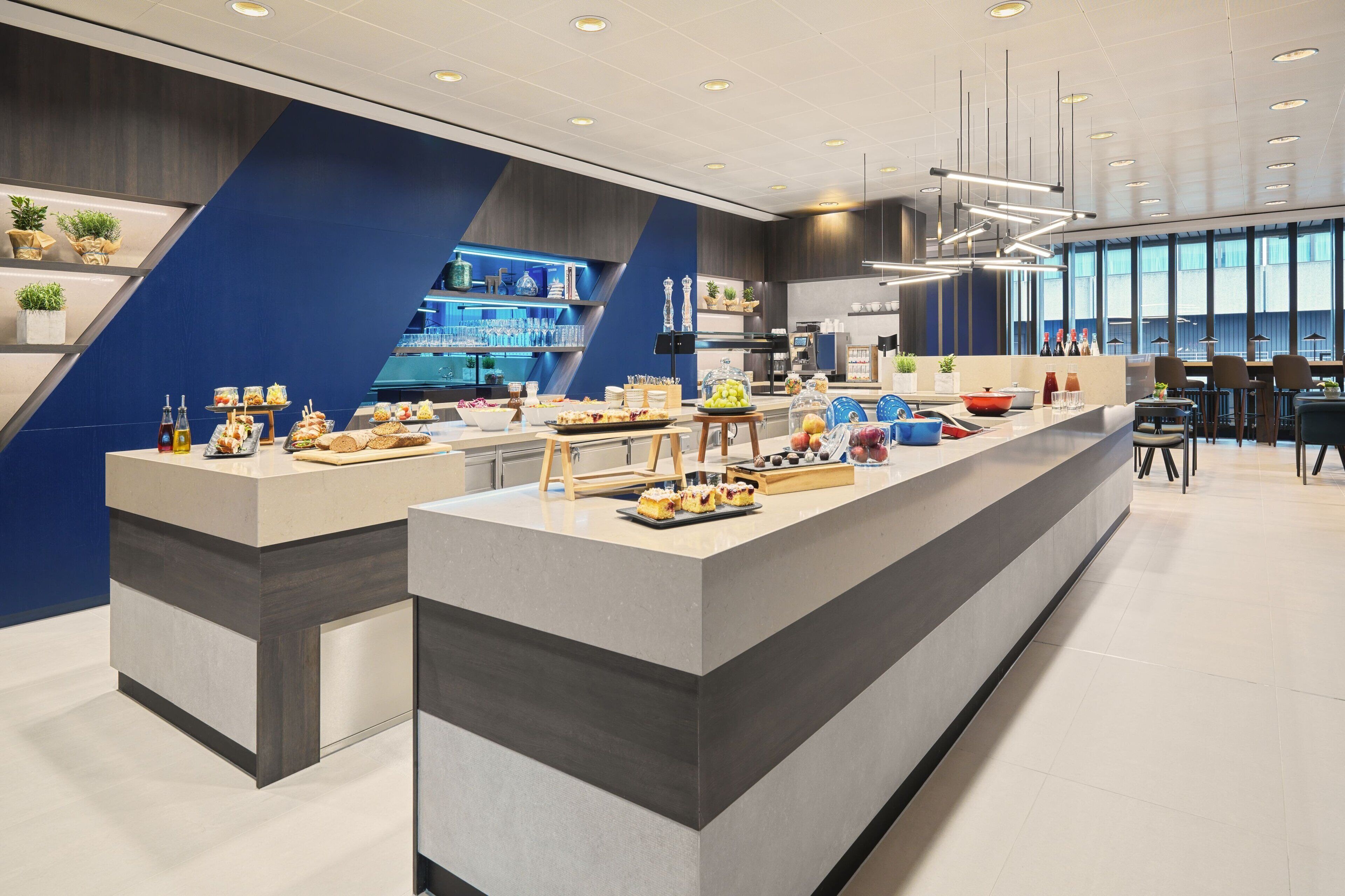 Une cuisine moderne dotée d’un îlot central, d’appareils électroménagers intégrés et d’un espace repas avec des chaises et des tables.