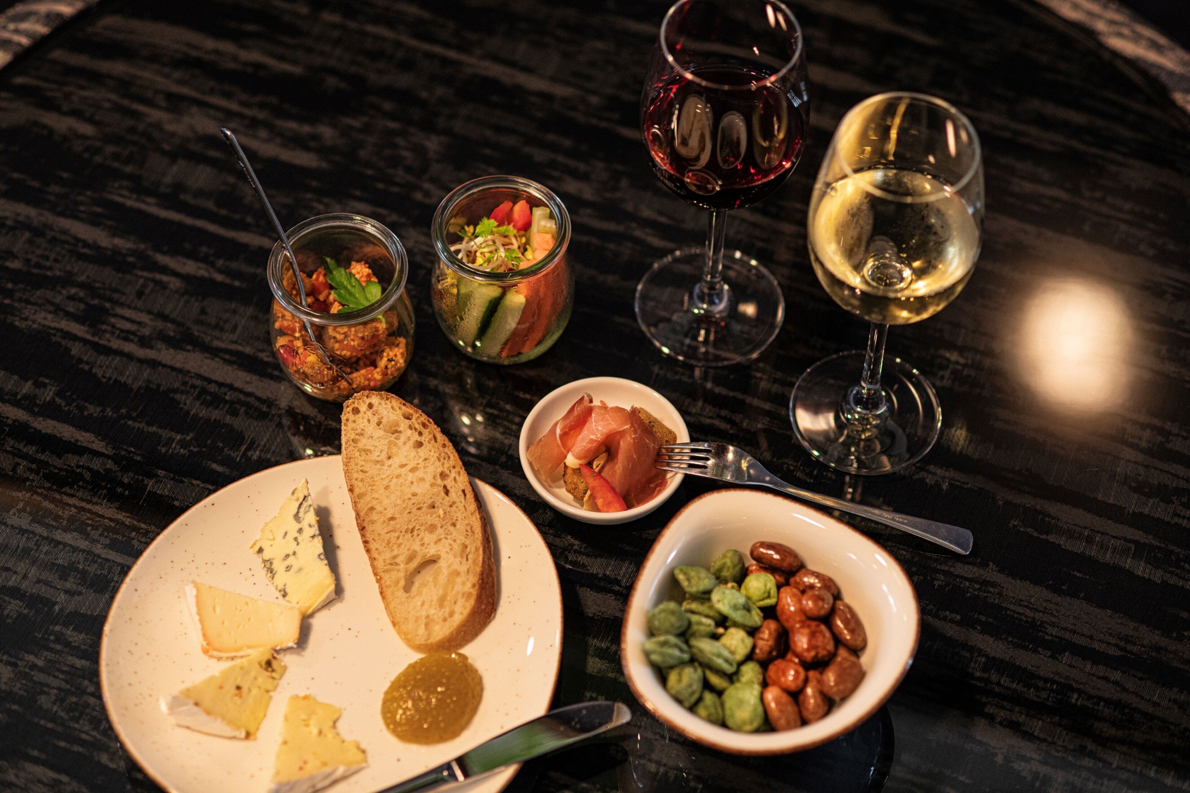 A table with various food items and glasses of wine.