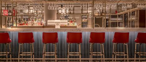A bar area with stools and a counter stocked with bottles and glasses.