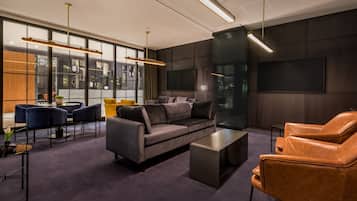 Una sala moderna con sofá, sillón, mesa de centro, ventanas amplias y un televisor de pantalla plana.