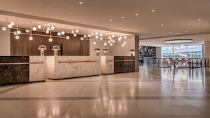 Una moderna zona de recepción con mostradores de mármol, iluminación colgante y un vestíbulo amplio.