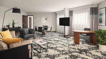 A modern living room with a sofa, coffee table, and a dining area with chairs and a table.