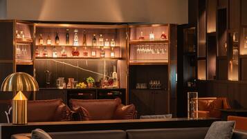 A bar area with multiple shelves of bottles and glasses, a bar counter, and leather seating.