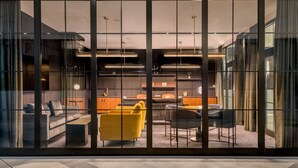 Un interior moderno con un sofá modular, un sillón amarillo y una zona de comedor con mesa y sillas.