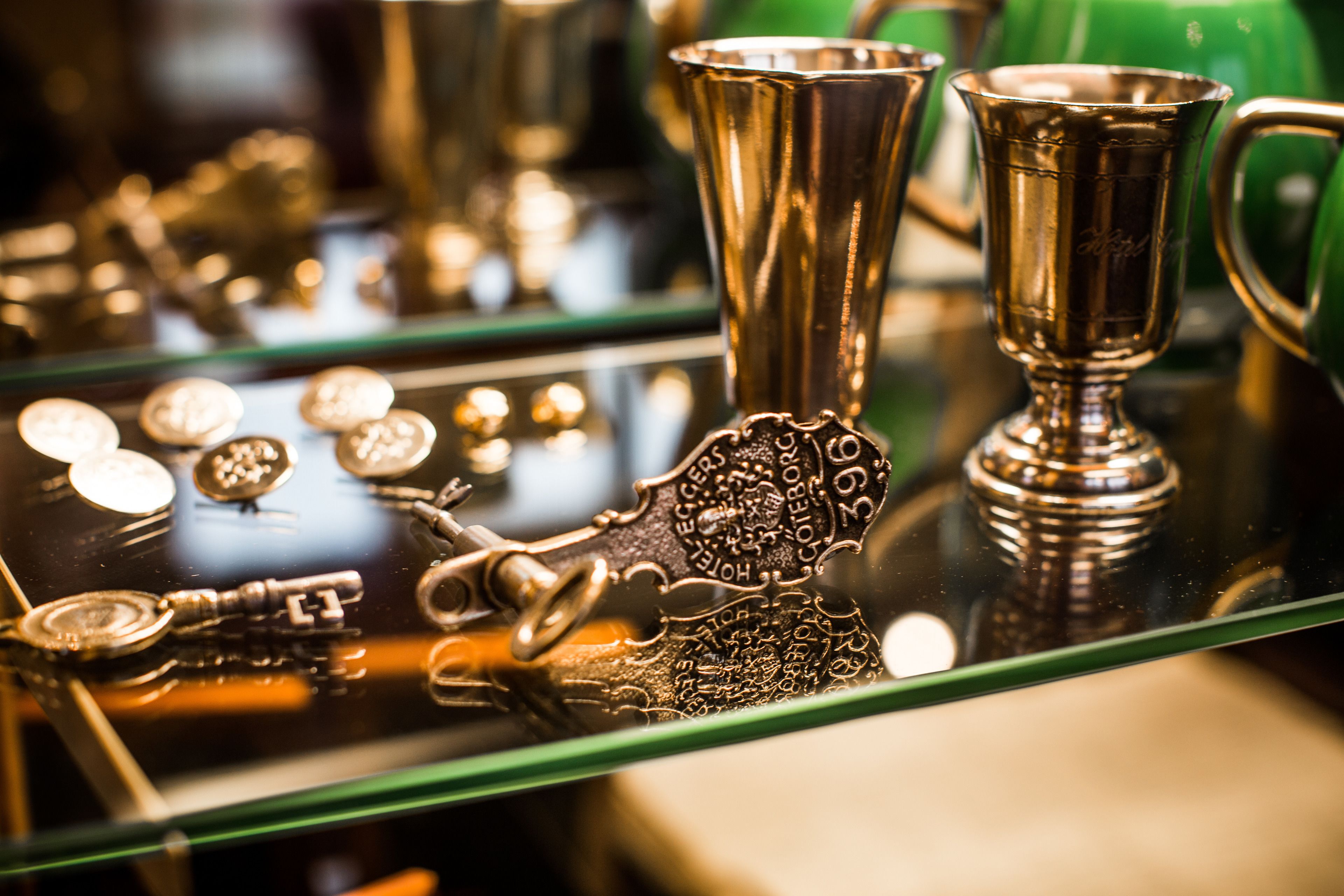 A display of antique silverware and keys on a reflective surface.