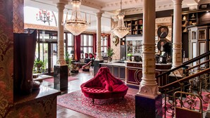 A grand lobby with a red velvet sofa, ornate chandeliers, and a staircase. - Hôtel Eggers (Gothenburg)
