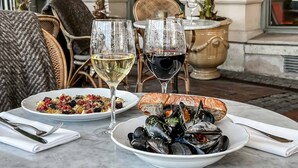 A table set with a plate of mussels, a bowl of salad, a slice of bread, and two wine glasses. - Hôtel Eggers (Gothenburg)