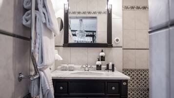 Un baño con lavamanos, espejo, toallero y artículos de aseo.