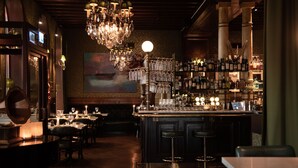 A bar area with a bar counter, stools, and a chandelier. - Hôtel Eggers (Gothenburg)