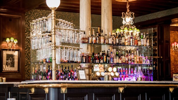 A bar area with a glassware display, shelves of liquor bottles, and decorative lighting. - Hôtel Eggers (Gothenburg)
