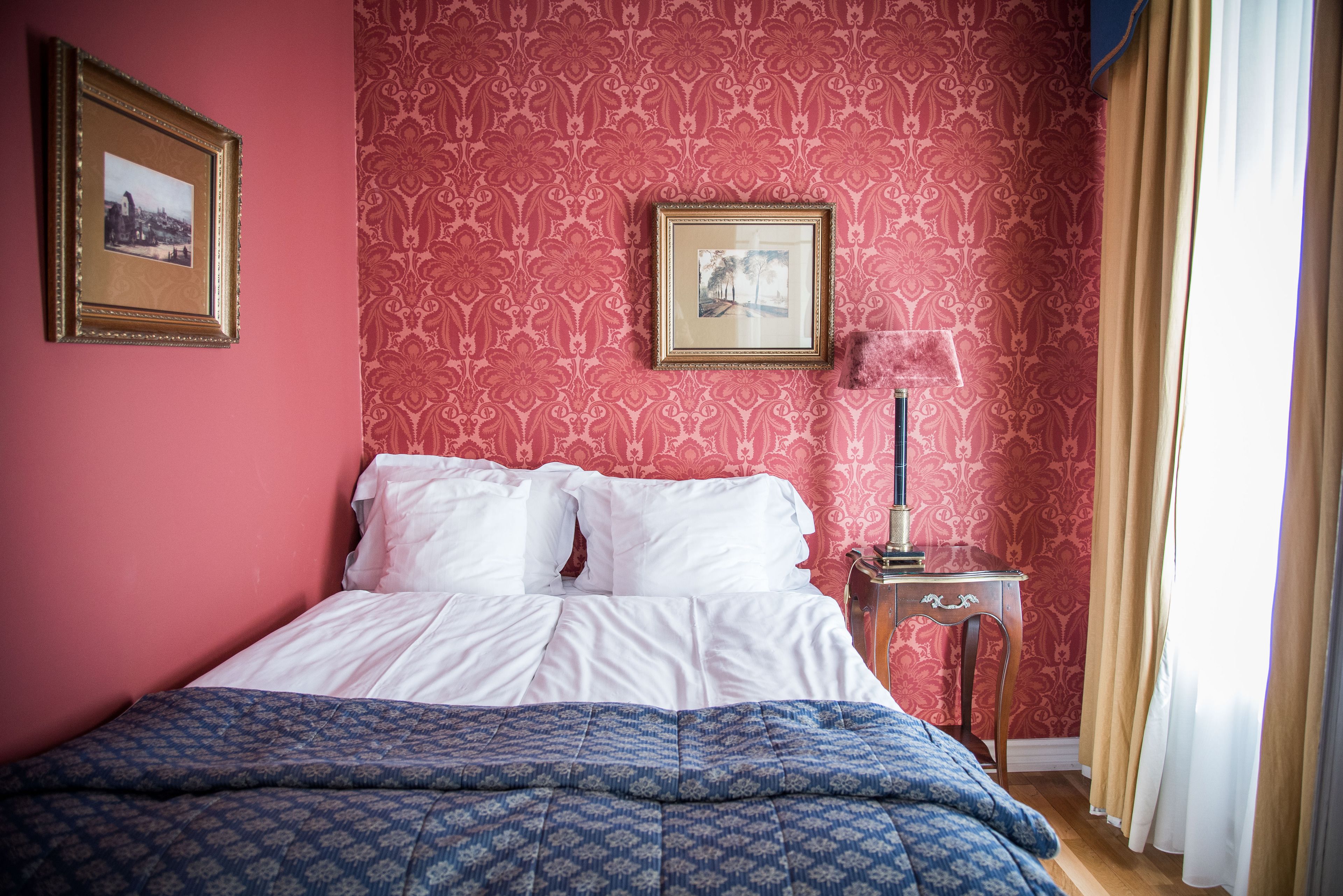 A neatly made bed with white linens, a blue patterned bedspread, and a framed picture on the wall.
